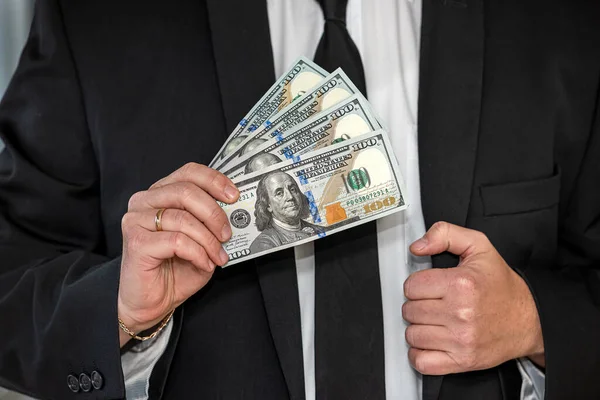 Takım elbiseli genç adam cebine dolar koyuyor. Rüşvet veya yolsuzluk kavramı