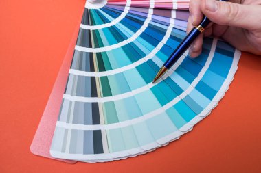 Turuncu üzerine izole edilmiş tekerlek paleti rengini seçen bir adam. Renk paletiyle çalışan kadın 