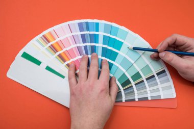 Turuncu üzerine izole edilmiş tekerlek paleti rengini seçen bir adam. Renk paletiyle çalışan kadın 