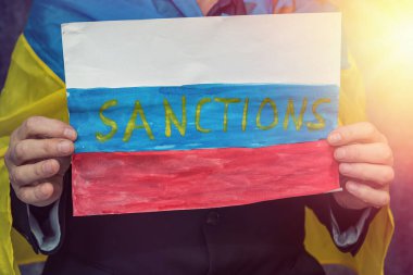 Ukraynalı adamın elinde Rusya 'ya ekonomik yaptırımlar içeren bir poster var. Saldırganın ve uluslararası teorisyenin çöküşü.