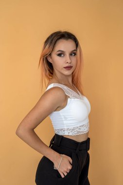 Sıradışı figürlü ince siyah saçlı kız turuncu arka planda güzel poz veriyor. Turuncu arka planda model kız konsepti