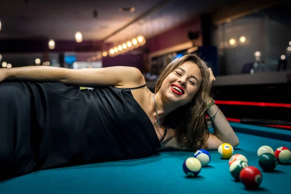 Beautiful lady lying on green snooker table among the balls. lifestyle