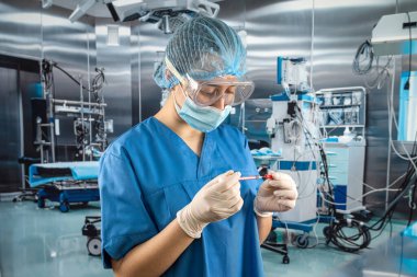 Mavi üniformalı genç bayan doktor elinde şırıngayla hastayı bekliyor.