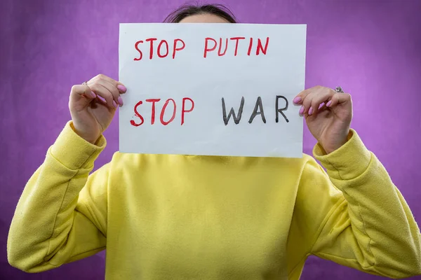 female hands is holding a poster with says stop war.  Protester hands