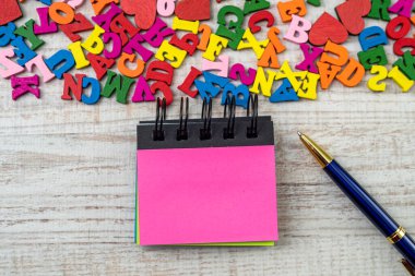 Eğitim masasında boş bir not bulunan küçük ahşap renkli harfler. ABC