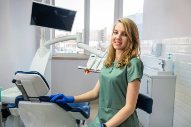 İş yerindeki dolapta üniformalı ve eldivenli genç, güzel dişçi stomatolojisi. Sağlık sigortası. Arkadaş canlısı doktor.