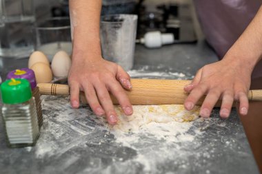 Güzel, genç, dişi eller güzel bir hamur yoğurmak için una yumurta kırıyorlar. Yemek pişirme konsepti