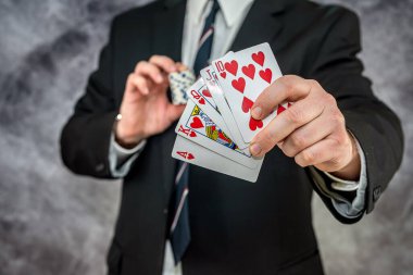 Siyah takım elbiseli şık bir adam kumarhanede oyun kartları ve poker fişleri tutuyor. Kumar oynama konsepti