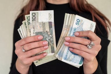 100 zloti 'lik banknotları kapatın. Polonyalı para zlotyleri bir yelpazeyi takım elbiseli bir kadın şeklinde tutuyor. Kadınların elindeki zloti kavramı.