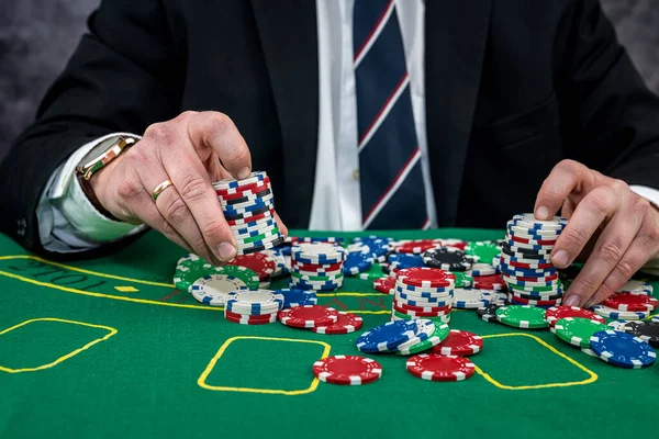 Male hand holding poker chips in casino green felt. Gambling concept