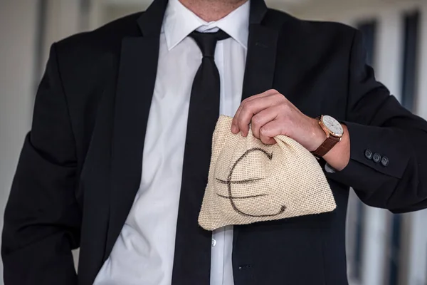 young boss businessman in expensive suit with tie holds bag with euro banknotes. Euro bag concept for man