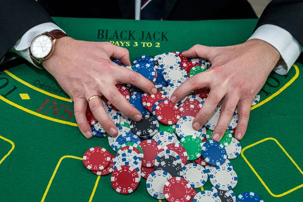 Male hand holding poker chips in casino green felt. Gambling concept