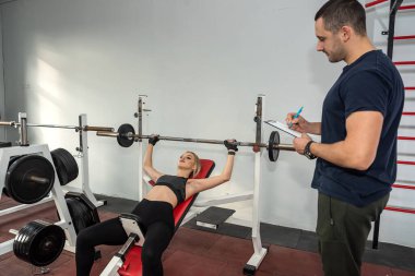 Poersonal eğitmeni olan bir müşteri spor salonunda egzersiz yapıyor. Abdominal mekik   