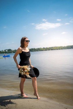 Çıplak ayaklı kadın gölde siyah elbiseyle yürüyor, yaz günü, yaşam tarzı.