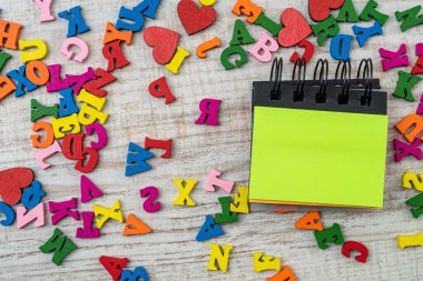 Eğitim masasında boş bir not bulunan küçük ahşap renkli harfler. ABC