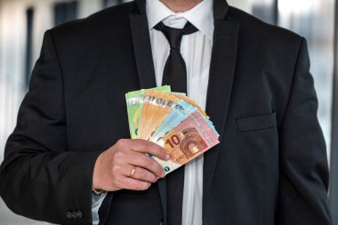 Takım elbiseli bir işadamı astlarına euro banknotları veriyor. Büyük bir şirkette finansal kazanç kavramı