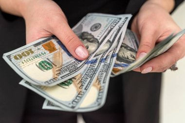 Siyah klasik takım elbiseli iş kadını güzel ellerinde bir sürü yeni dolar tutuyor. İş kadını ve iş konsepti