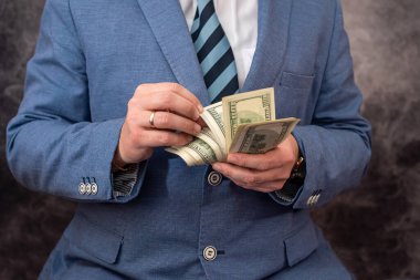 an outstanding man with beautiful strong hands has to hand over a large sum of dollars to the workers. Big and small business concept