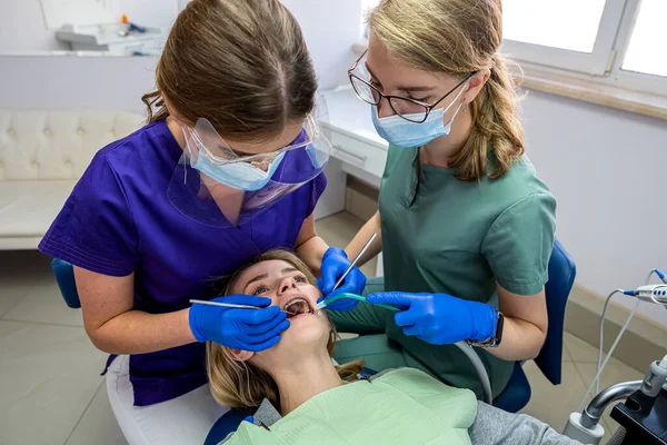 Profesjonalny Dentysta Asystentem Leczy Zęby Młoda Pacjentka Leżąca Krześle Dentystycznym — Zdjęcie stockowe