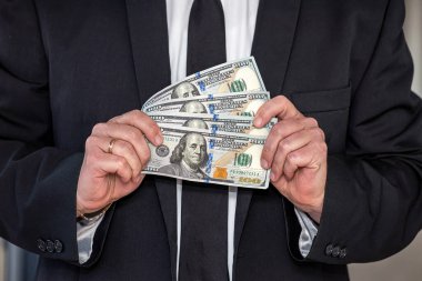 a man with a noble physique in a white shirt and tie shows a large sum of dollars in himself. Finance and profit concept