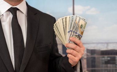 in the central office, the boss in a chic suit takes dollars out of his own pocket. Boss concept with a bunch of money