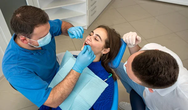 Dentista Profesional Con Asistente Trata Dientes Paciente Joven Acostada Una — Foto de Stock