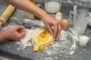 Noel kurabiyeleri için yumurta, yağ ve sütle hamur hazırlayan profesyonel bir kadın fırıncı. Lezzetli ev yapımı konsepti