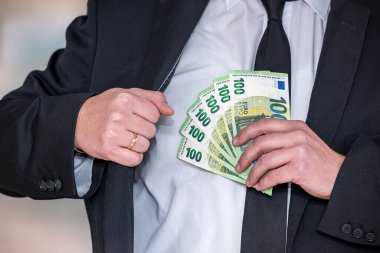 İş adamı elinde avro banknotları tutan siyah takım elbise giyer. Para kavramı