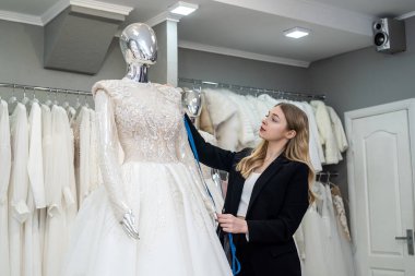 Mezuralı tasarımcı kadın atölyedeki gelinliği mankenle ölçtü