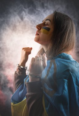 Rusya 'nın başlattığı savaş üzerine Ukrayna bayrağına sarılmış bir kadın feryat ediyor. Ukrayna için dua et, barış ve dünya için dua et.