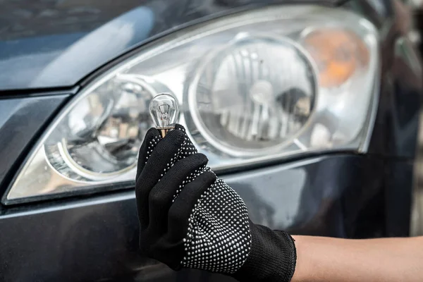 mechanic changing light bulb in his car. technology