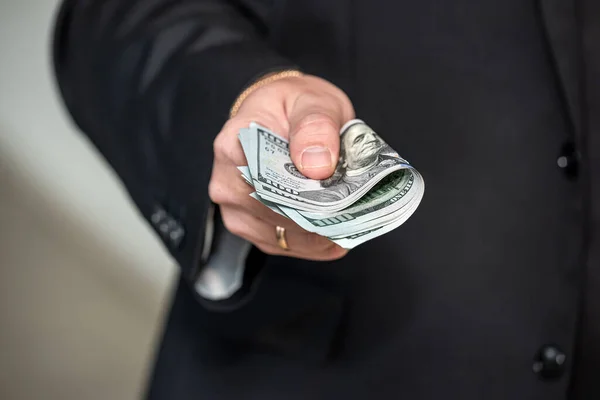 Closeup of hands of a businessman in suit giving cash money us dollars