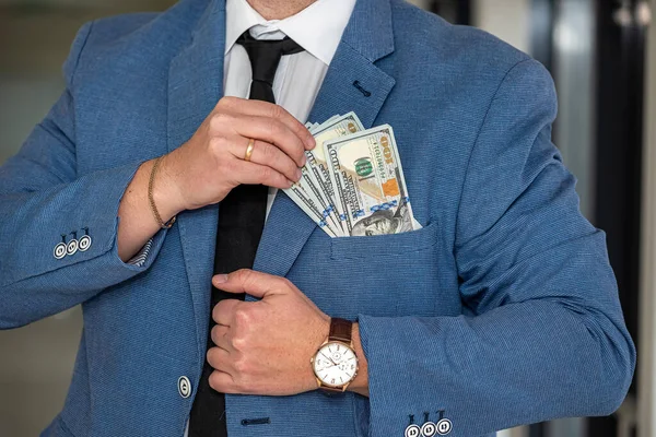 a man with a noble physique in a white shirt and tie shows a large sum of dollars in himself. Finance and profit concept