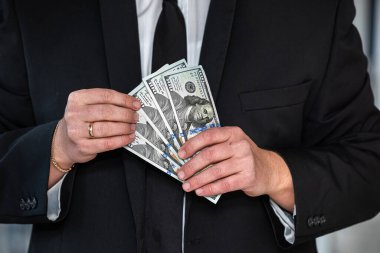 close-up of businessman's hand in branded suit holding dollar banknotes. The concept of very profitable investment.