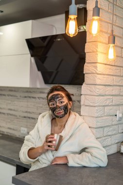 Evde pijamalı inanılmaz güzel bir kız kozmetik maske yaptı ve dizüstü bilgisayarla çalışıyor. Bir kızda kozmetik maske konsepti