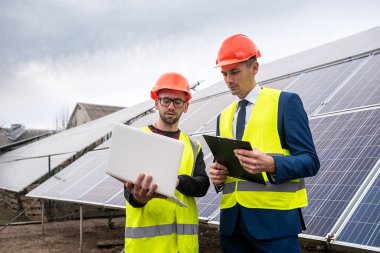 Özel giysiler içindeki yönetici, ekonomik panellerin kurulması pahasına özel giysiler içindeki işçiyle konuşur. Yeşil elektrik kavramı