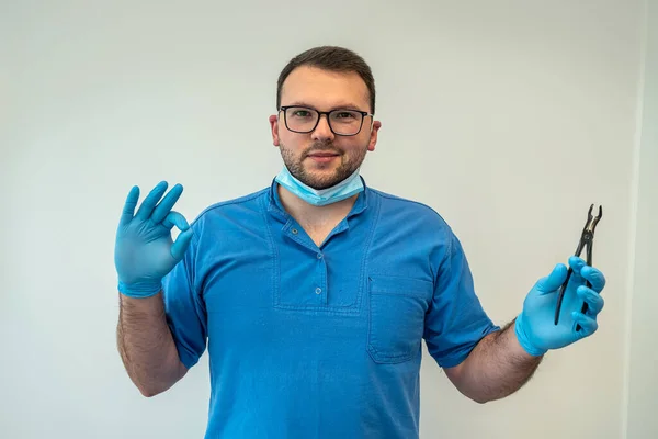 handsome male professional dentist sitting in his own dental office in medical clothes. Dentist concept in office