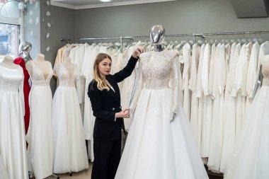 female dressmaker work at wedding salon with centimeter tape measure white elegant dress