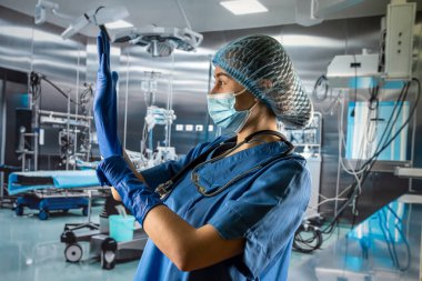 Bayan doktor ya da mavi ceketli hemşire kauçuk mavi eldivenler giyip hastayı ameliyathanede muayene etmeye hazırlanıyor.