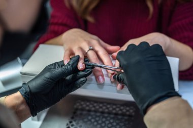 Manikürcü müşteriye güzellik salonuna vernik uygulaması için hazırlık prosedürleri uyguluyor. manikür konsepti