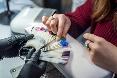 Güzellik salonunda vernik numune paleti ile mükemmel rengi seçmede usta asistanı. Manikür kavramı