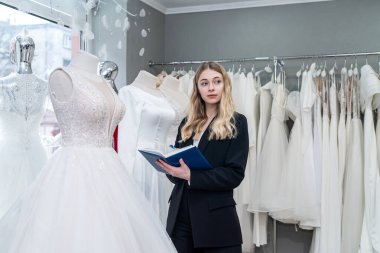 Modern düğün mağazasında notlar tutan güzel genç bir satış elemanı. Kadın gelinlik mağazası  