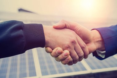 Tulum giymiş ve kast mensubu güç panelleri kurduktan sonra tokalaşan iki yakışıklı genç adam. Yeşil elektrik kavramı