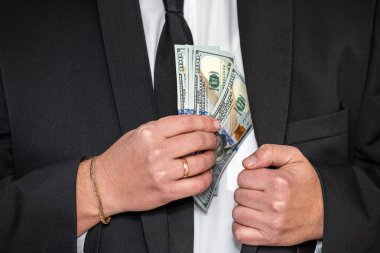 handsome young businessman in a stylish jacket from a suit with a large sum of dollars. Big and small business concept. Dollars in the hands of a man