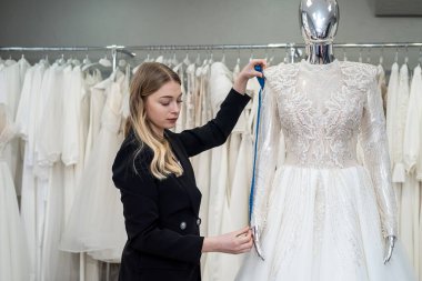 Mezuralı tasarımcı kadın atölyedeki gelinliği mankenle ölçtü