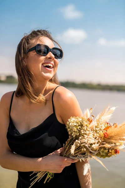 Charming Young Lady Black Dress Sunglasses Holding Bouquet Flowers Enjoys — Stock Fotó