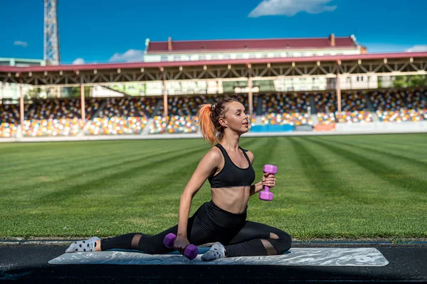 Young fitness woman wear sportswear doing workout with dumbbells on fresh air sity stadium. sport as active lifestyle