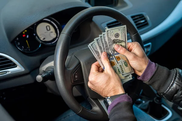 hands of a strong man holding dollar bills in the car. Car concept. Business concept