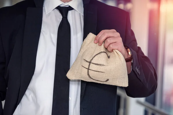 young boss businessman in expensive suit with tie holds bag with euro banknotes. The concept of a large sum of euros in a bag