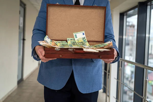 a man in a classic suit stands with an open case in which a large amount of money for the arrangement. The concept of a large sum of money to negotiate